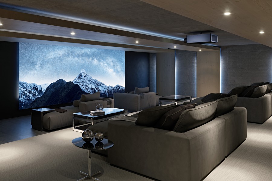 A home theater with chaise lounges, a large screen displaying snow capped mountains, and a Sony projector.