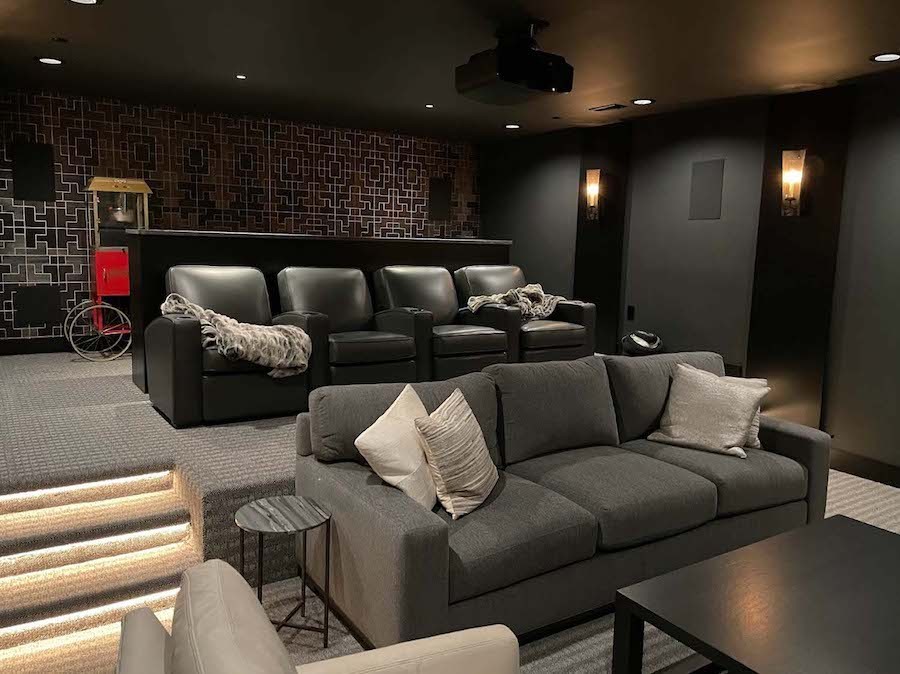 two tiers of home theater seating with plush black and gray fabric. A popcorn machine sits behind it.