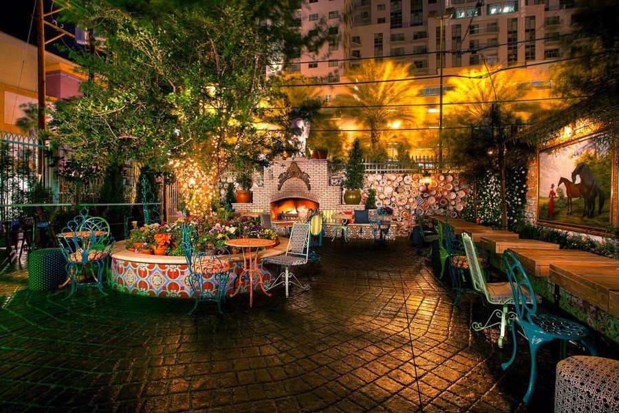 A colorful patio area of a restaurant in a city at night.